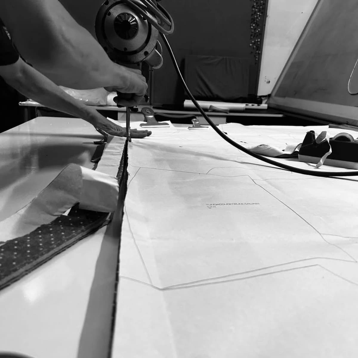 Fabric being cut through stacked pattern pieces at a partner workshop table