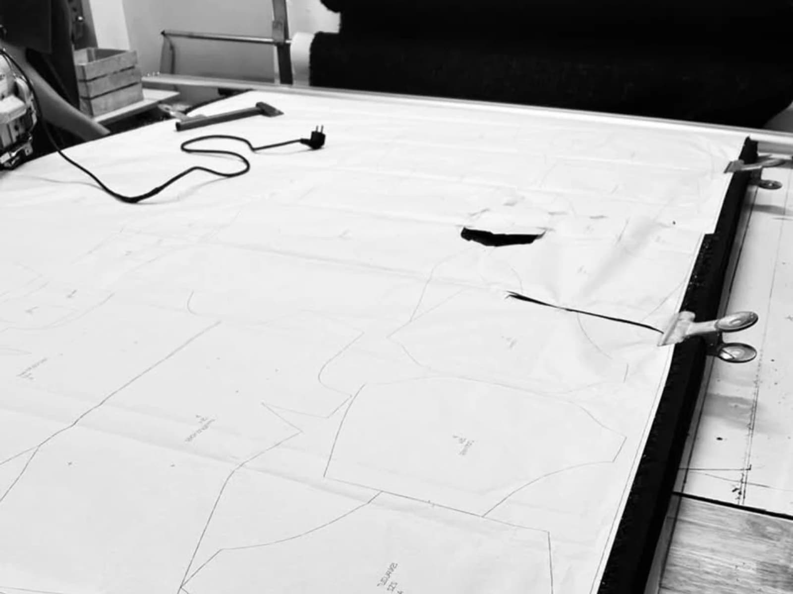 Garment pattern pieces arranged across a partner workshop cutting table