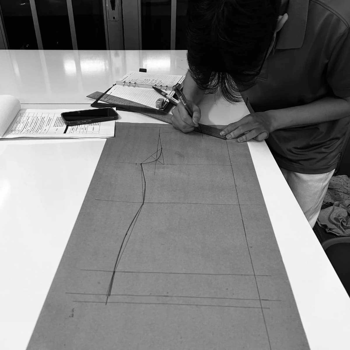 Pattern maker drafting a garment block at a partner workshop table